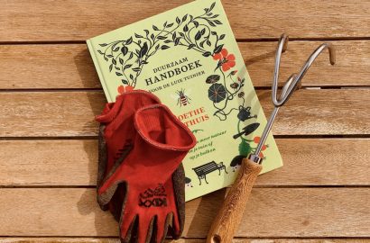 lenteklussen in de tuin: tuinboek, tuingereedschap en rode werkhandschoenen