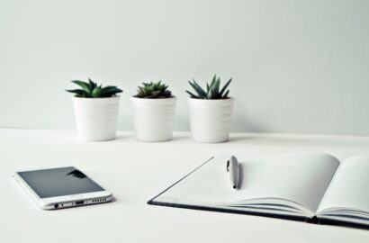 Notitieblok en telefoon om het nieuwe jaar te plannen met drie cactussen op de achtergrond