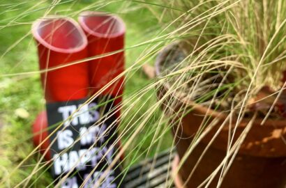 tuinieren; rode laarzen met siergras en kaartje et tekst This is my happy place