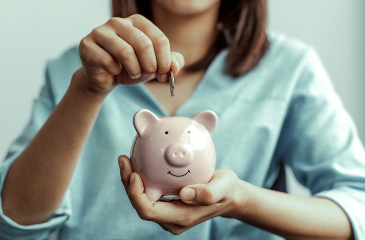 Vrouw doet geld in spaarvarken aan het einde van de maand als resultaat van sparen met je Notes-app