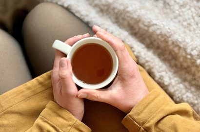 Close up van iemand met kop thee in haar handen. Persoon op de foto is Janneke zelf, eigenaar van blog jannekeswereld.nl