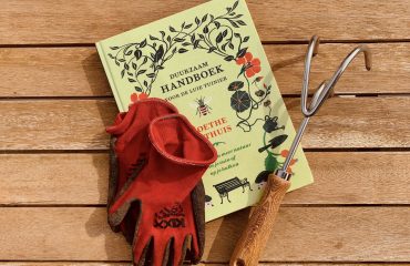 lenteklussen in de tuin: tuinboek, tuingereedschap en rode werkhandschoenen