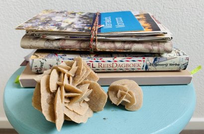 Reisverslag maken: stapeltje met reisverslagen en woestijnrozen op voorgrond