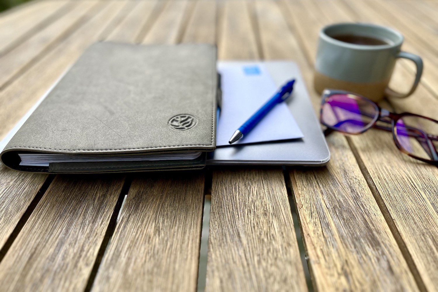 afbeelding met laptop, notebook, pen, kop drinken en bril