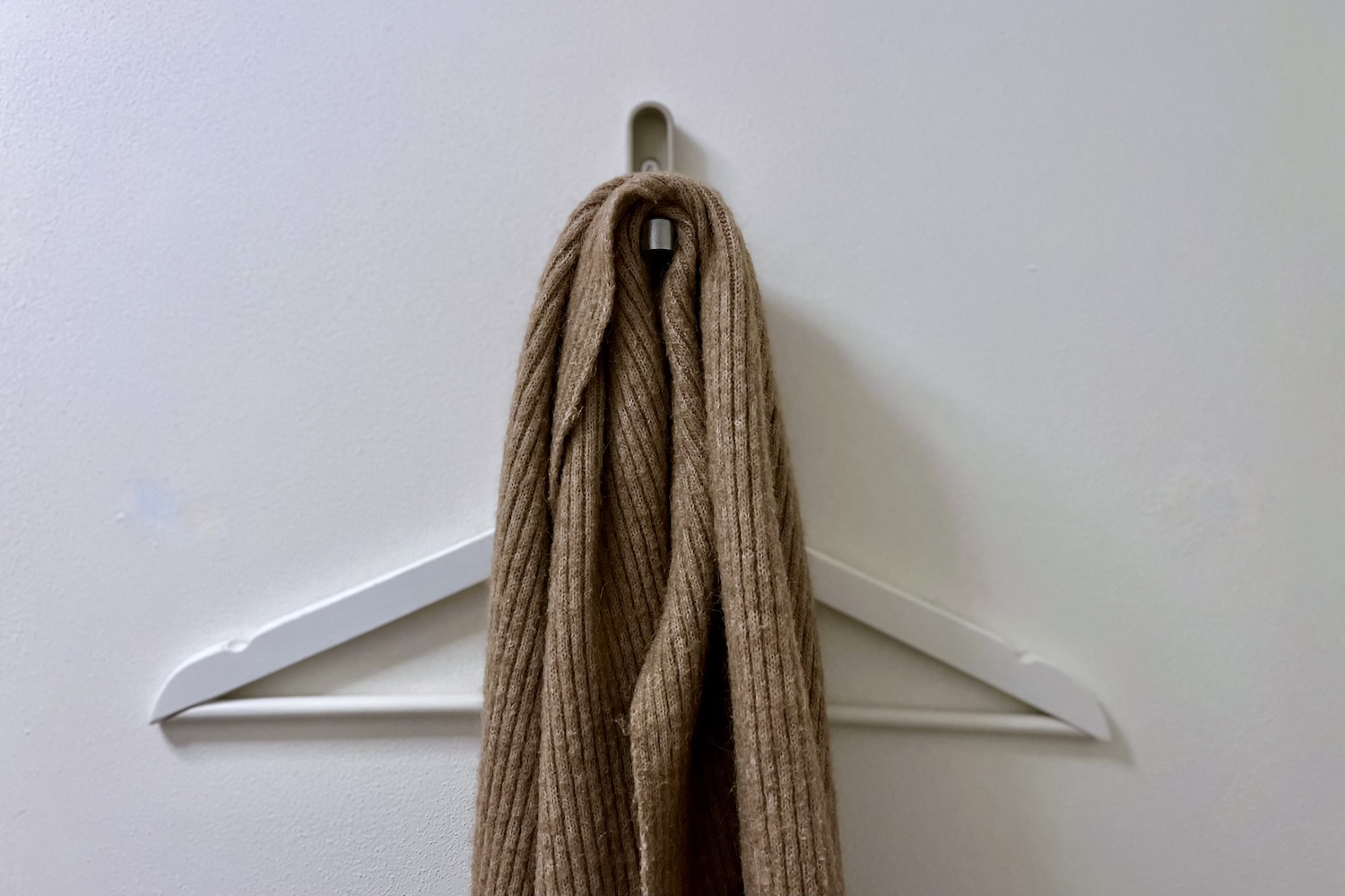 Witte kledinghanger op kapstok met sjaal, bij blog over minimalistische wintergarderobe