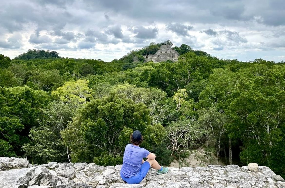 Janneke uitkijkend over het regenwoud naar Estructura 2 in Calakmul, Mexico