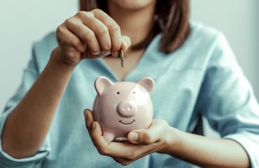 Vrouw doet geld in spaarvarken aan het einde van de maand als resultaat van sparen met je Notes-app