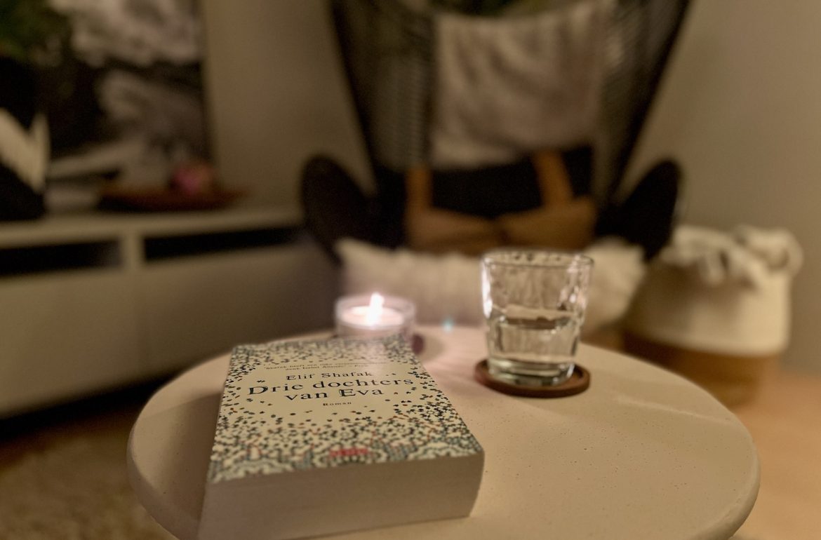 foto van interieur met boek, glas water, boek met stoel op achtergrond als fijne plek in donkere dagen
