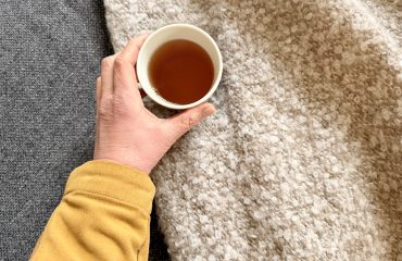 Hand met kop thee tegen een tweekleurige achtergrond. Bezinnende stemming en passend als hoofdfoto bij artikel over 50 worden en de overgang